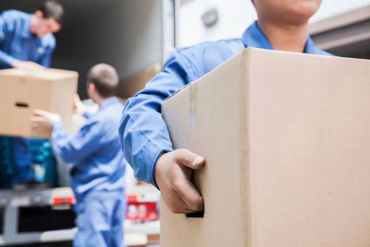 A man holding a box in front of another man.