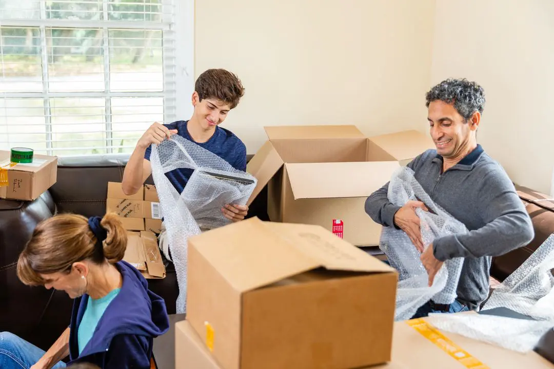 A group of people in the living room with boxes.