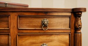 An ornate wooden chest with drawers and cabinets. The drawers have decorative metal lion head handles.